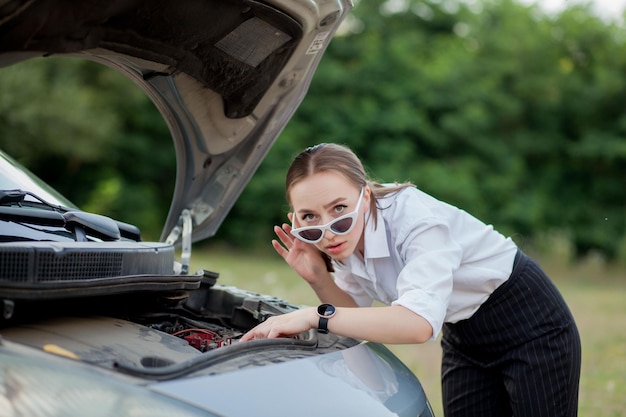 Young woman by the roadside after her car has broken down She opened the hood to see the damage