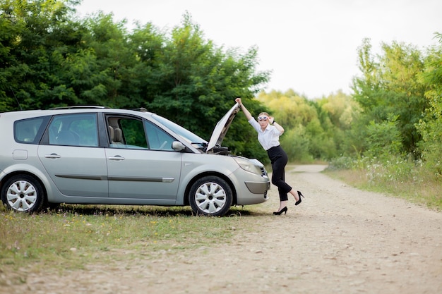 Young woman by the roadside after her car has broken down She opened the hood to see the damage.