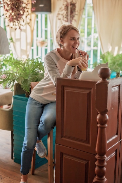 カウンターの後ろのカフェにいる若い女性が飲み物を飲みます。