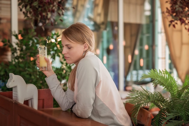 カウンターの後ろのカフェにいる若い女性が飲み物を飲みます。