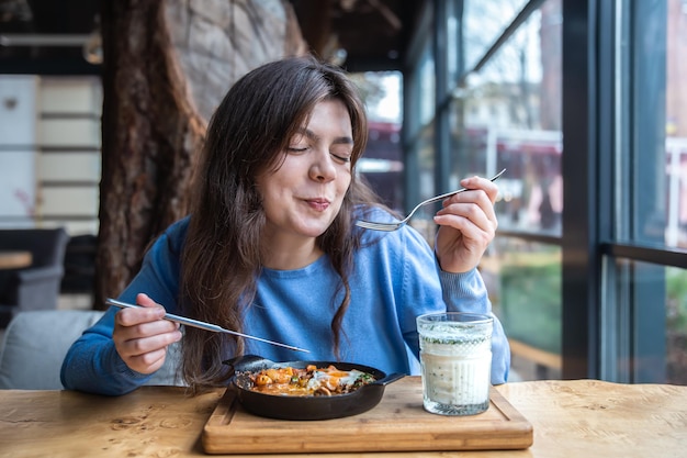 a young woman in a cafe dines on traditional shakshuka and ayran
