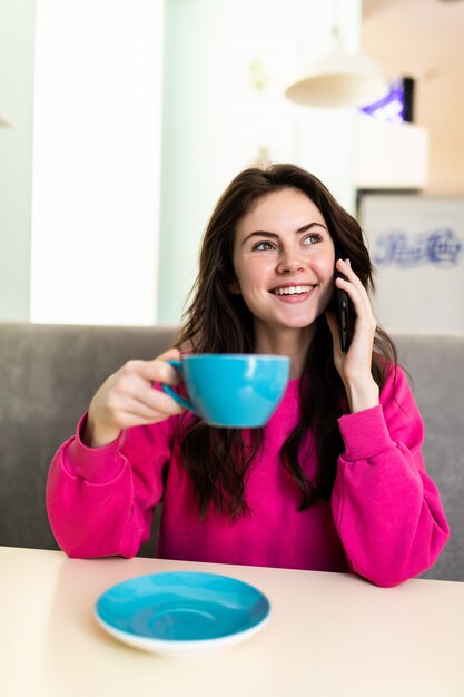 コーヒーを飲みながら、電話で話しているカフェで若い女性