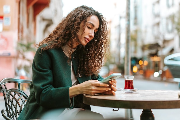 Photo young woman in a cafe reading a message from her mobile phone