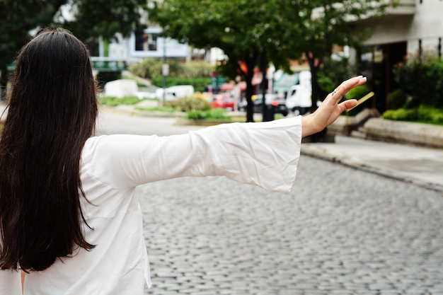 写真 若い女性が通りでタクシーを呼びます。