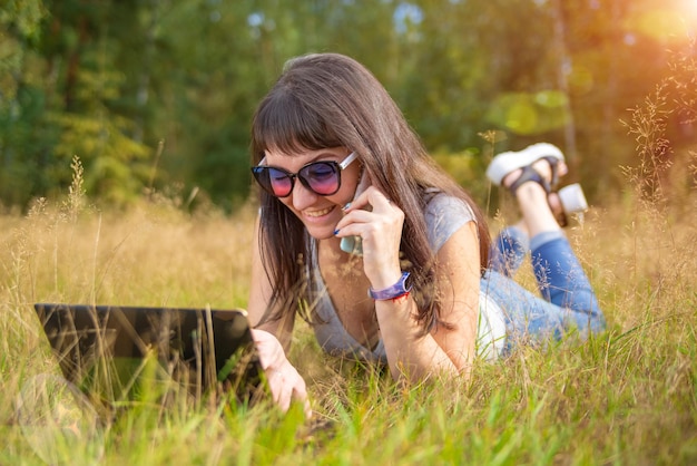 Young woman calling by phone and smiling happy pointing in laptop