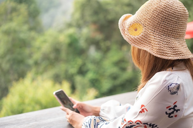 帽子をかぶって携帯電話で遊んで顔が見えない若い女性