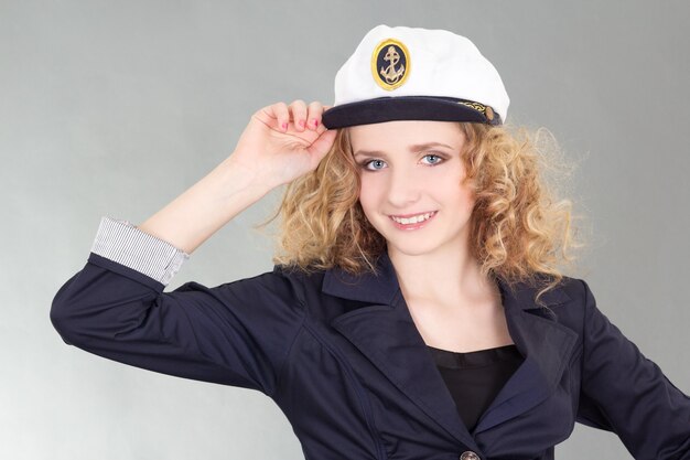 Young woman in captain cap over grey