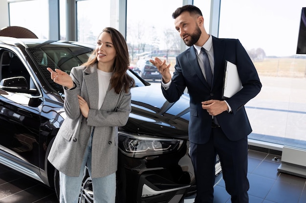 A young woman in a car dealership together with an employee a car dealer chooses a new car car rental concept