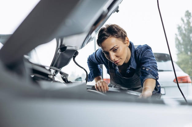 Foto meccanico di automobile della giovane donna che controlla automobile al servizio dell'automobile