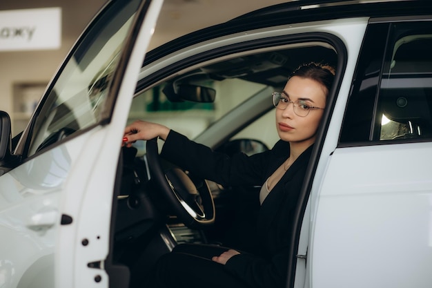 Young woman in a car showroom choosing a car