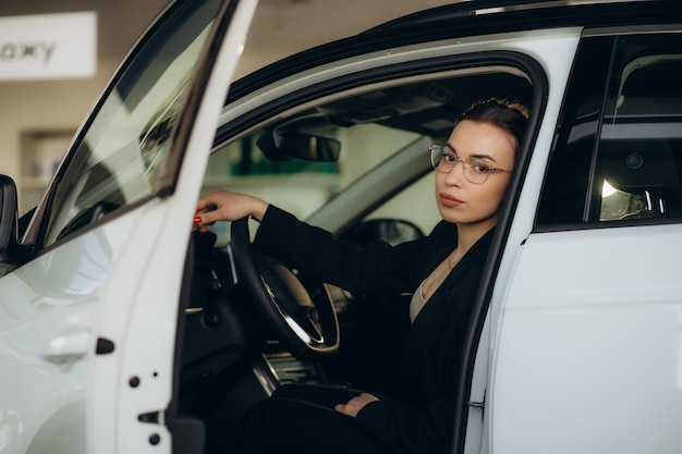 自動車ショールームで車を選ぶ若い女性