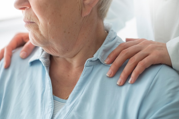 Young woman caregiver supports an elderly woman patient.