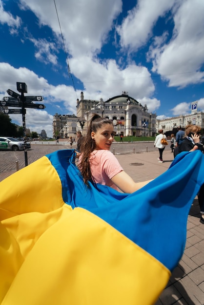 Young woman carries the flag of Ukraine fluttering behind her