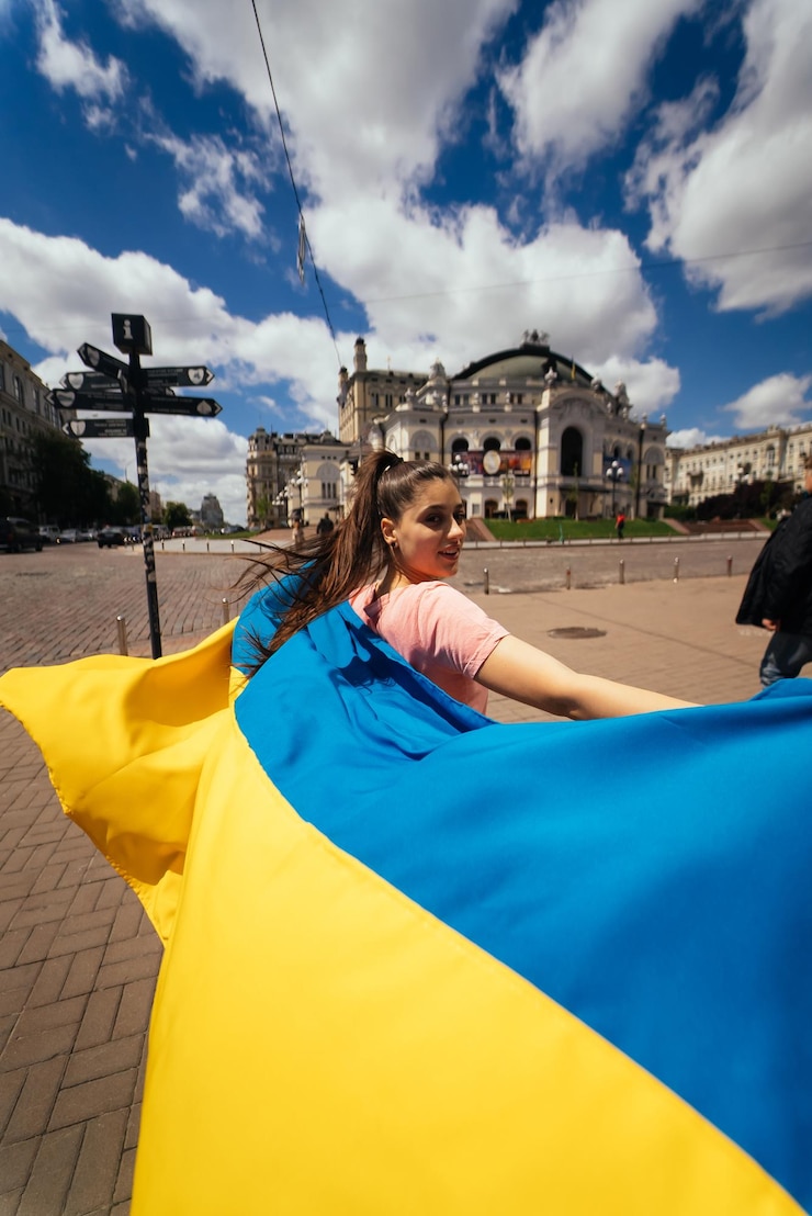 Фотография молодая женщина несет за собой развевающийся флаг украины