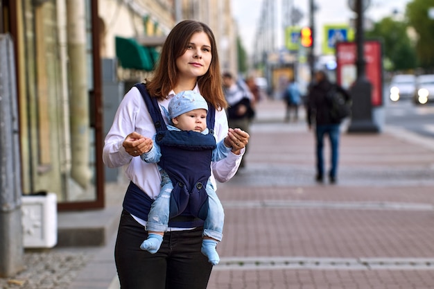 Young woman carries infant in baby sling on moskovsky prospekt in st petersburg russia