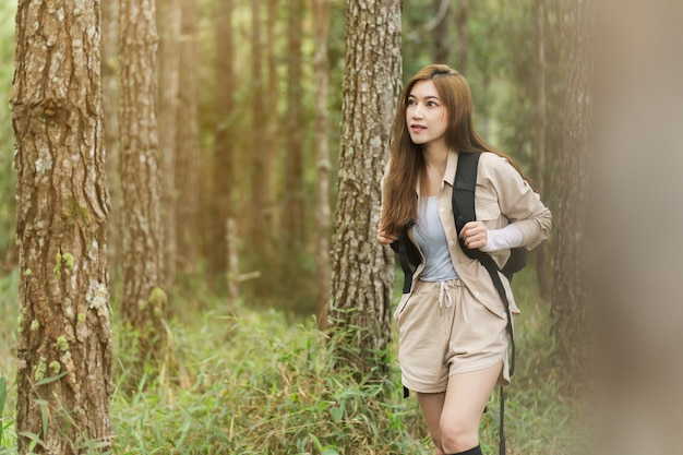 バックパック旅行を運ぶと森の中を歩く若い女性