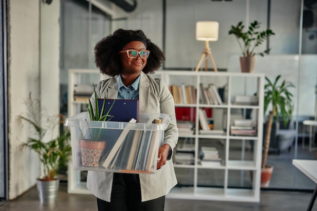 Young woman carrying office supplies in plastic box