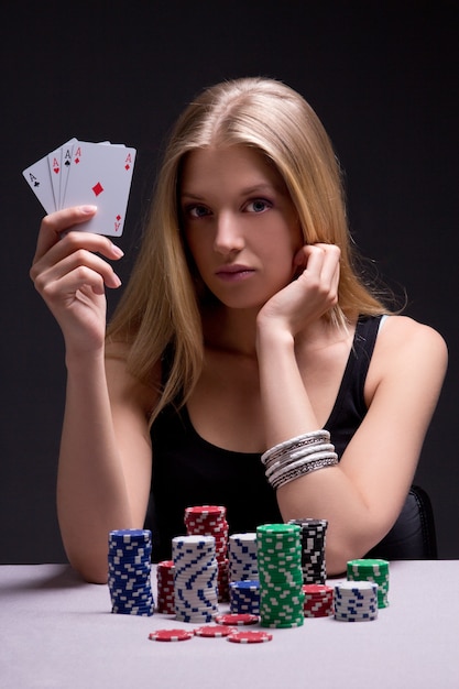 Young woman in casino with cards and chips over grey background