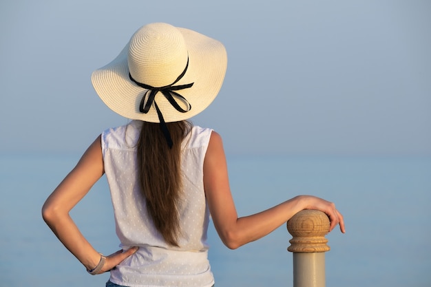 暖かい夏の日に海辺でリラックスしたカジュアルな服装の若い女性。