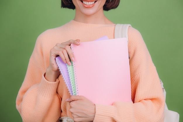 Young woman in casual peach sweater isolated on green olive color wall