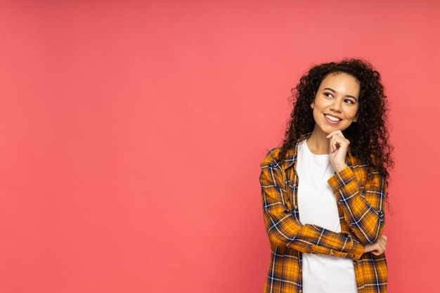 ピンクの背景にカジュアルな服装の若い女性