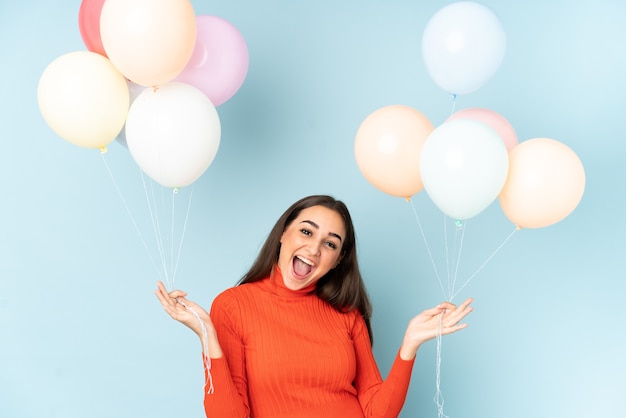 Young woman catching many balloons