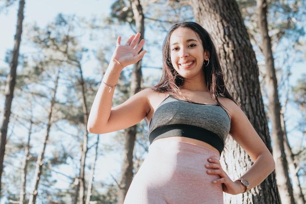 Young woman celebrates exercise saluting to camera with copy\
space happy young people training during a sunny summer day\
preparing for the beach body training clothes