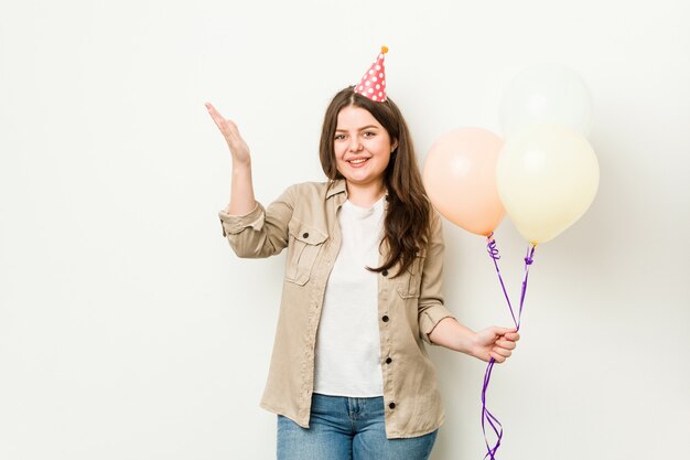 즐거운 놀라움을 받고, 흥분과 손을 올리는 생일을 축하하는 젊은 여자.