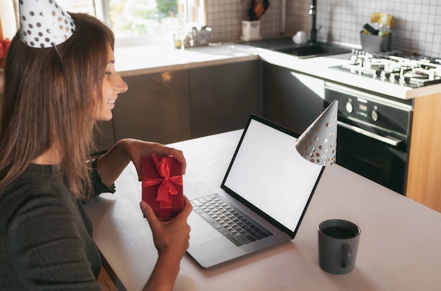 Young woman celebrating her birthday at home with friends on video call