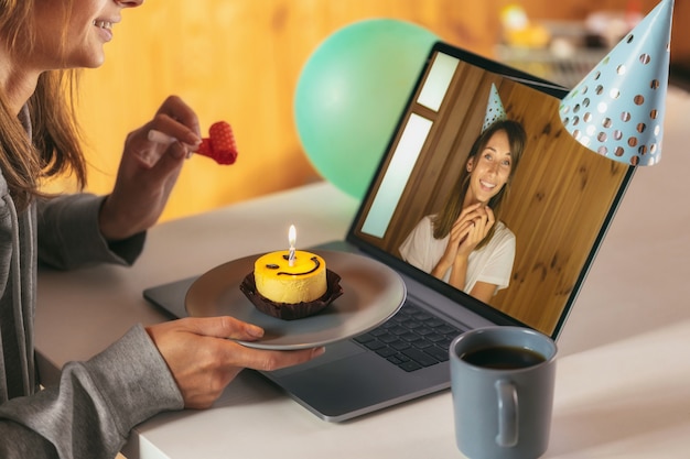 ビデオ通話で友人と自宅で彼女の誕生日を祝う若い女性