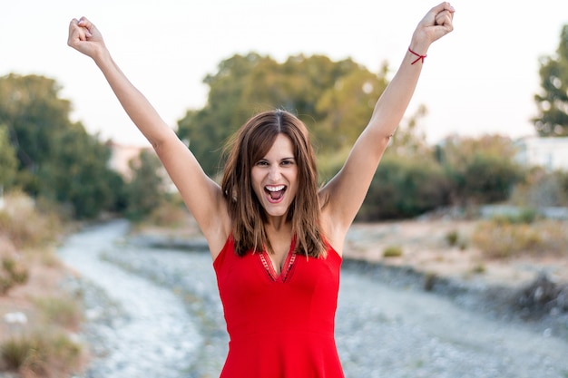 Photo young woman celebrating victory with a red dress