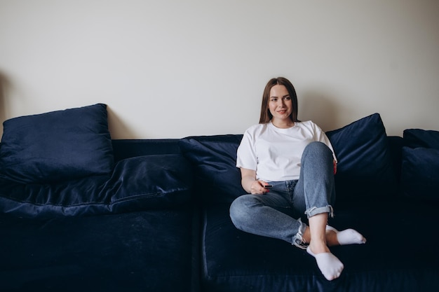 Young woman changing channels with remote control