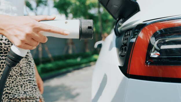 Foto giovane donna carica la batteria dell'auto ev all'aperto