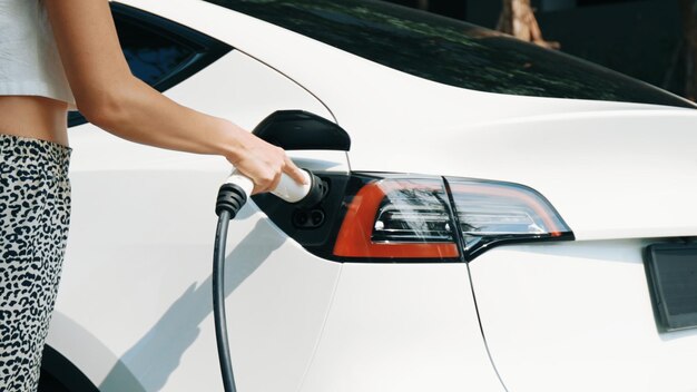 Young woman charge ev car battery outdoor innards