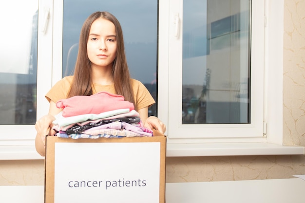 A young woman at a charity Foundation holds a box of clothes for cancer patients