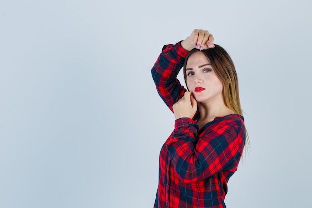 Young woman in checked shirt making vogue pose and looking attractive , front view.