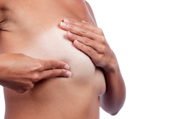 Young woman checking breast (auto self exam) for anomalies, nodes or weird lumps for breast cancer.