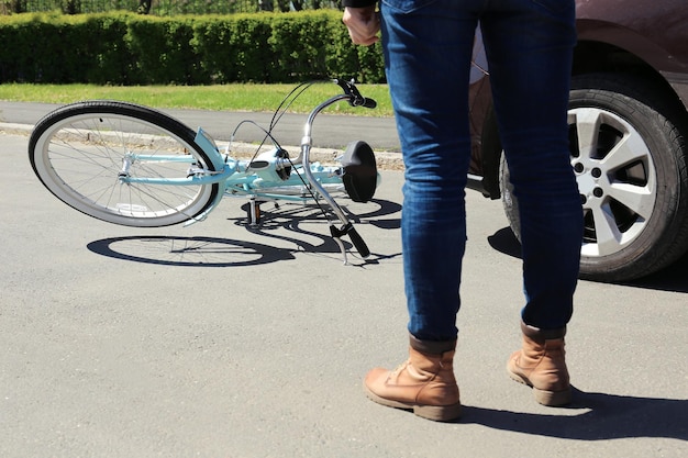 写真 路上で車と自転車の事故の結果を確認する若い女性