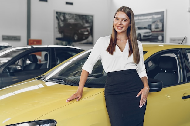 Young woman checking out a new car she is going to buy in car salon