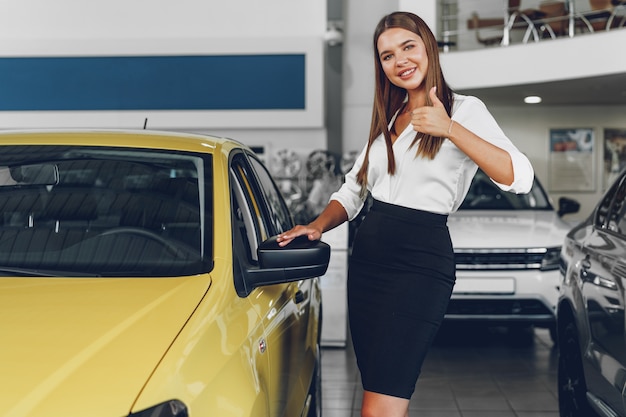 Young woman checking out a new car she is going to buy in car salon