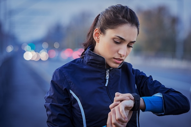 写真 通りを走った後の時間をチェックする若い女性