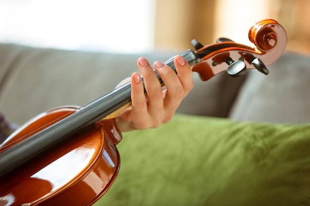 Giovane donna che controlla un violino a casa.