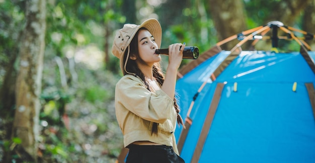 写真 キャンプテントの前に飲み物を飲む若い女性の ⁇ 声