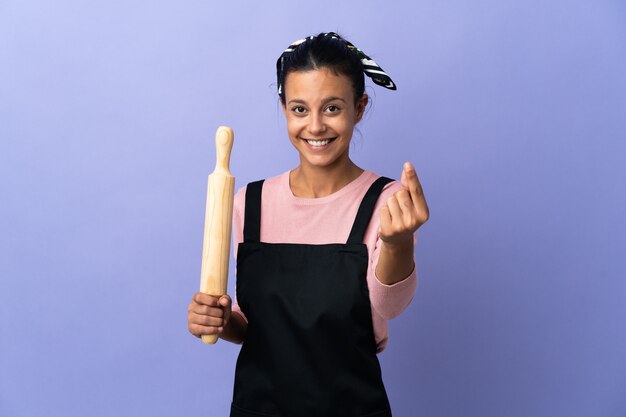 Young woman in chef uniform making money gesture