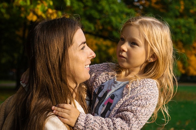 公園で喜んで抱きしめる若い女性と子供の女の子