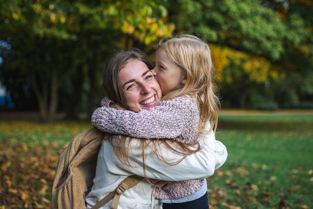 Young woman and child girl joyfully hugging in the park