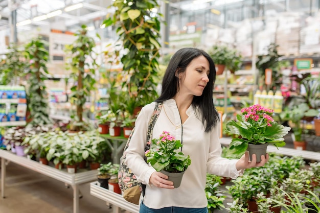 Молодая женщина выбирает комнатные растения в цветочном магазине