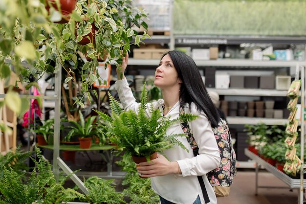 젊은 여자는 꽃집에서 실내 식물을 선택합니다