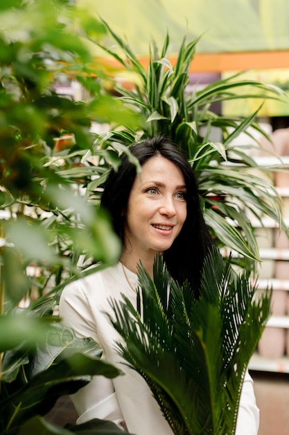 若い女性はフラワーショップで屋内植物を選択します