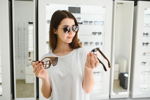 a young woman chooses on sunglasses in an optics store